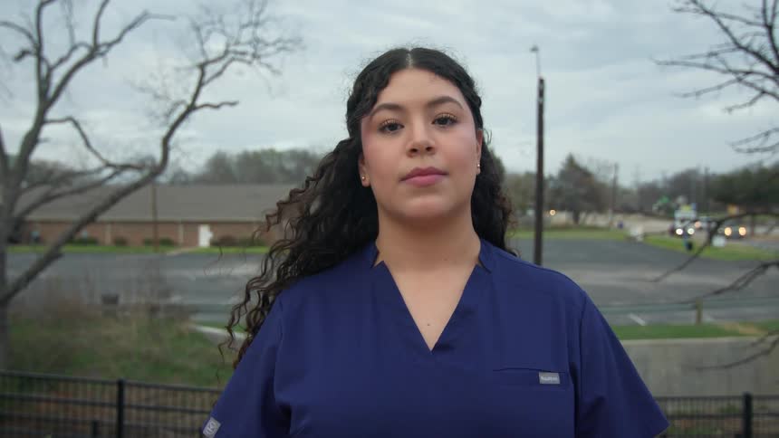 Portrait of a young curly-haired woman outdoors wearing a blue work shirt