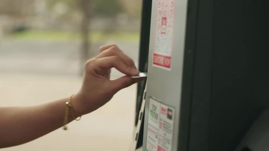 A woman puts her credit card in the gas pump to pay