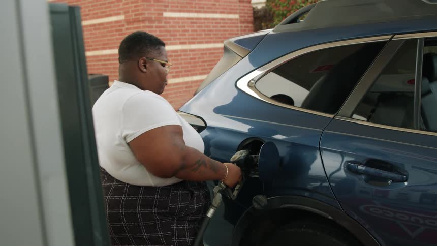 Woman putting the valve on the fuel tank of her blue suv vehicle and filling up