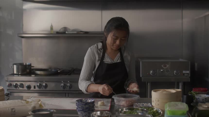 Woman in the kitchen preparing small pasta with raw nukiman dumplings meat