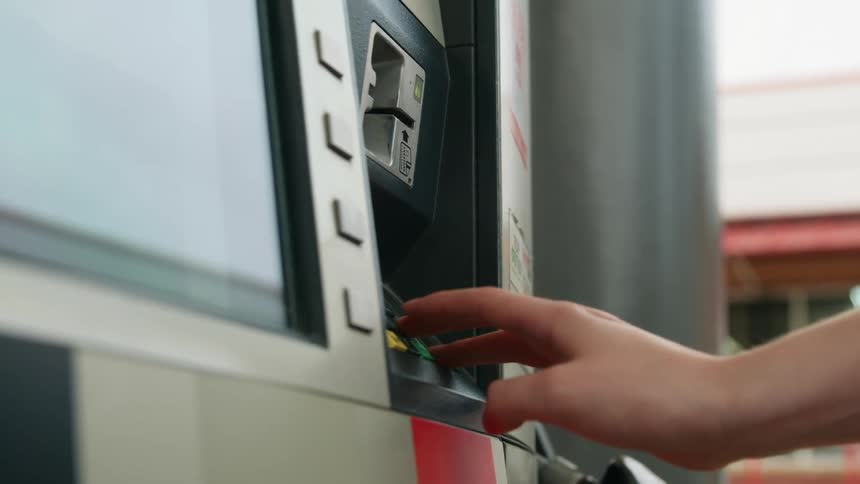 A persons hand typing on a machine at a gas station