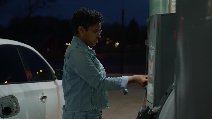 A woman inserts her card into a gas pump debit machine purchasing gas