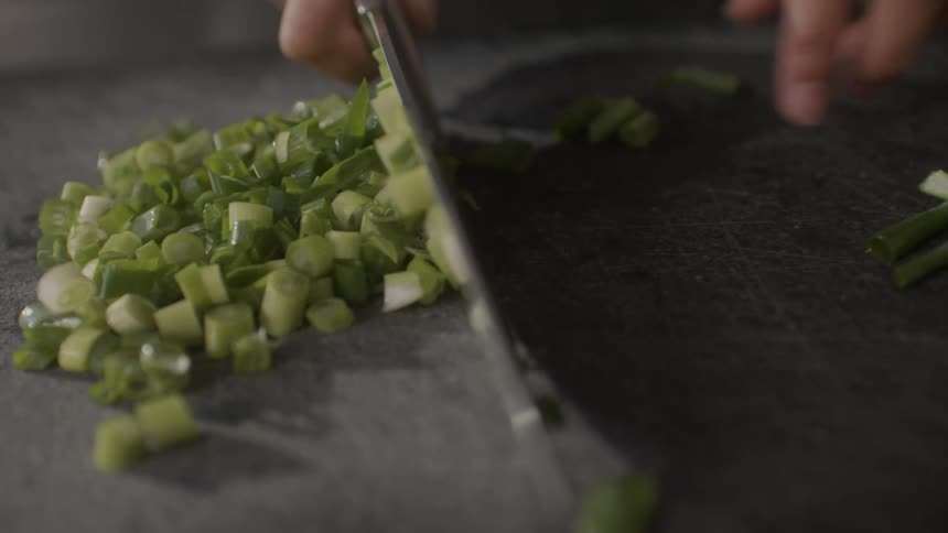 Cook cuts up vegetable then picks most of the slices up with the knife