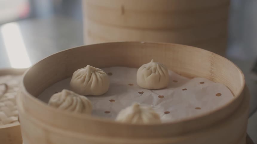 Small chinese buns inside a wooden steam cooking bowl
