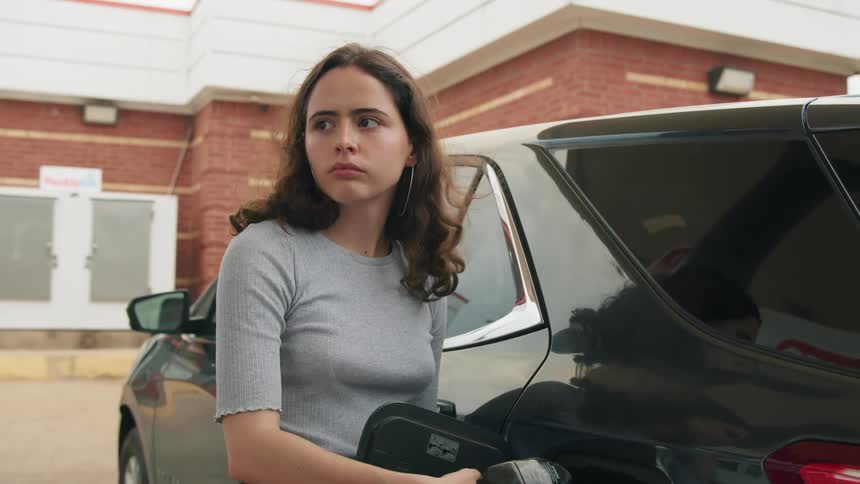 Young woman at a gas station fueling her suv vehicle