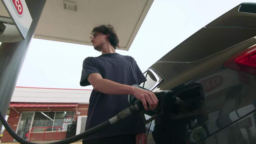 Man filling up his vehicle and checking the gas pump