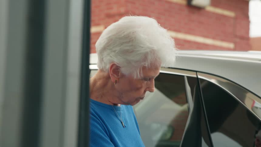 Elderly lady filling up her vehicle at a gas station