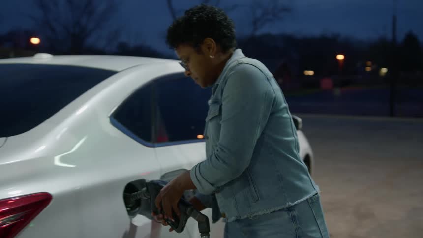 A woman fills her car with gas