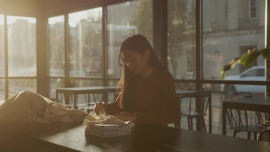 An asian female worker is folding napkins on the counter