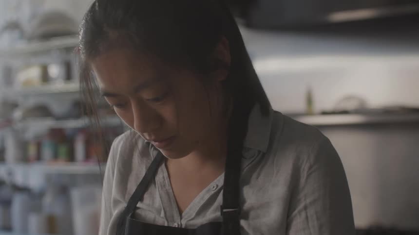 Woman fills dumpling dough in a kitchen with a window that shows nearby street