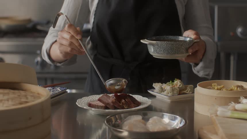 A person putting gravy on some meat on a plate