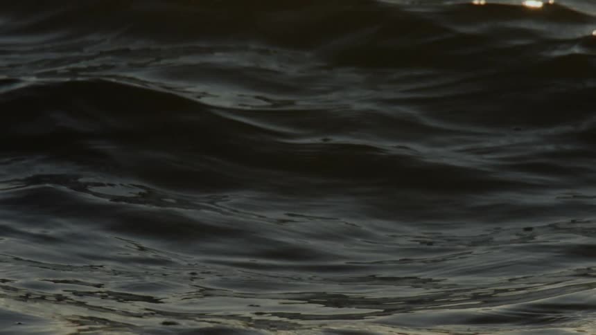 Ocean waves moving in slow motion as sunlight flickers through