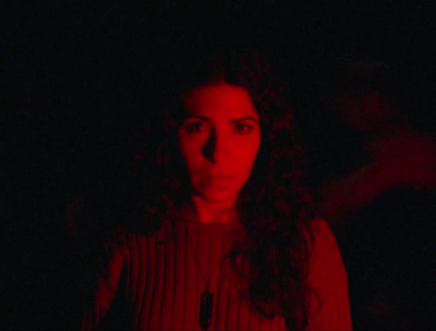 Rapid movement occurs around woman standing under changing colored lighting