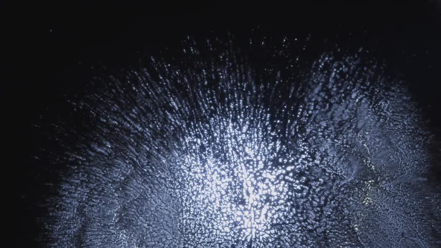 Textured surface surrounded by darkness glows brightly at the center