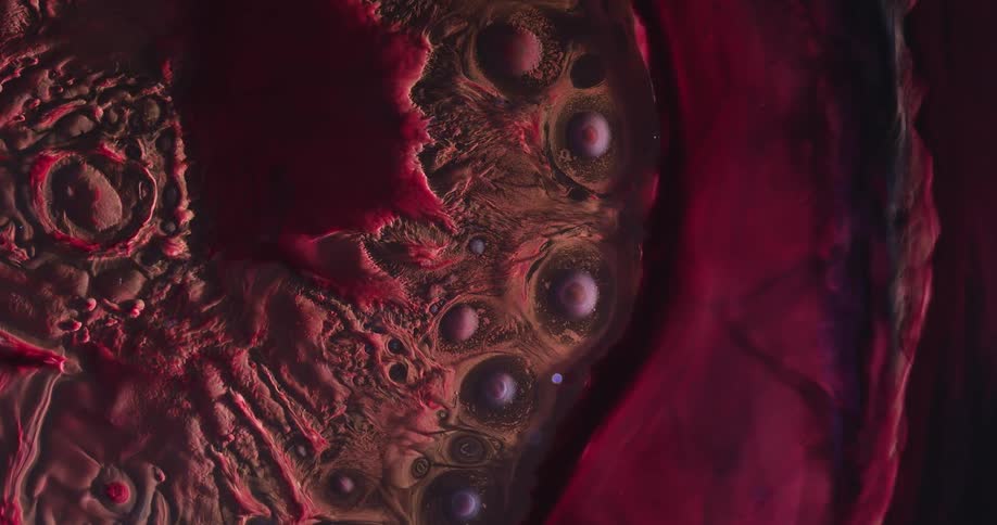 Extreme closeup on a dense reddish fluid expanding in an abstract way and in slow motion