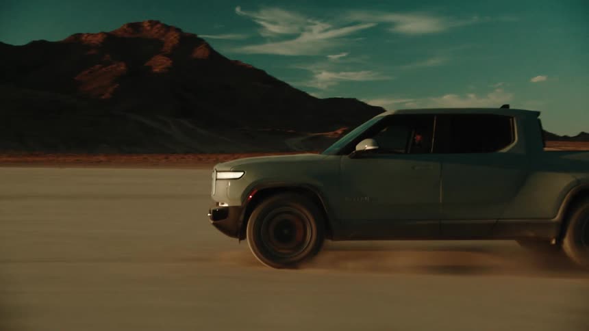 Truck drives very fast through the desert in front of a mountain