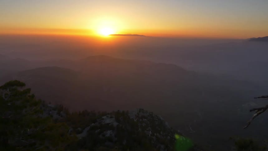 An aerial view of the sun setting behind mountains