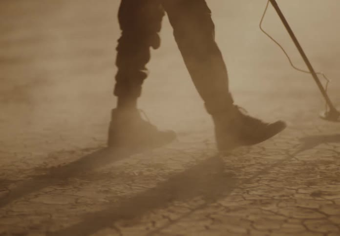 A man is using his metal detector in the desert