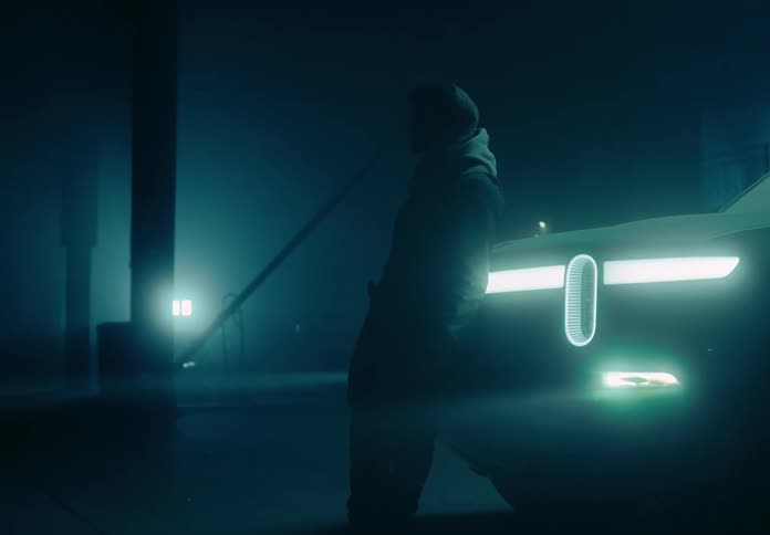 A man leaning against a truck outdoors at night
