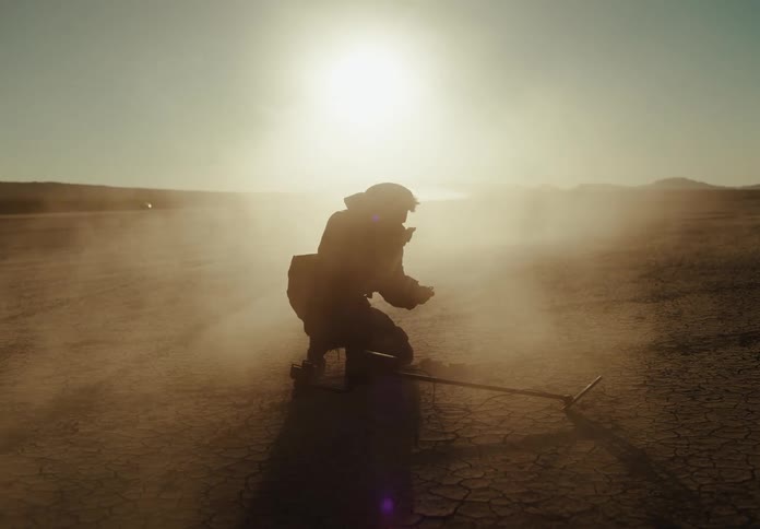 Man holding a metal detection device and finding an object on dry desert ground