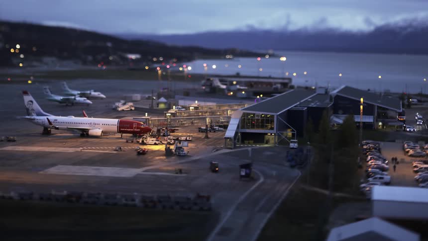 People boarding an airplane and airport crew preparing the plane
