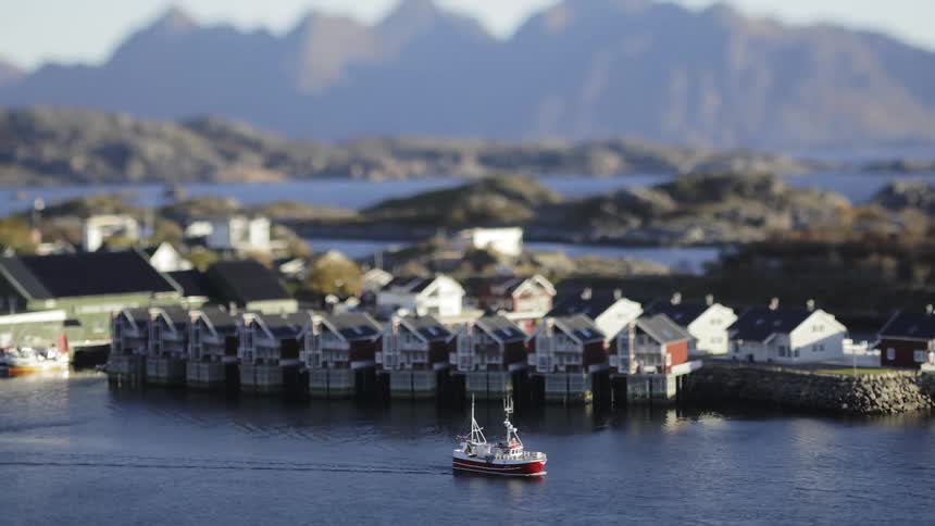 A fishing boat passes the homes on the shore