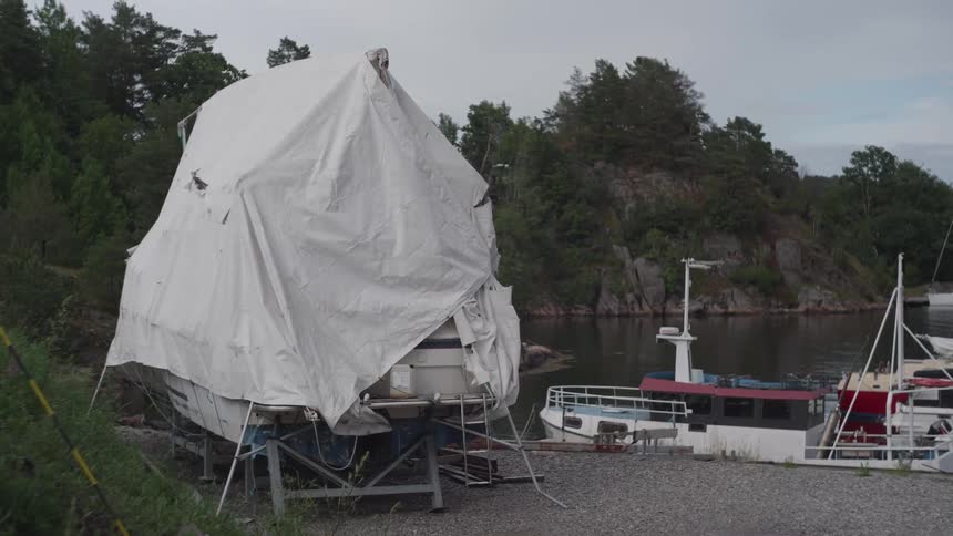 A boat on land next to a harbor covered in tarp