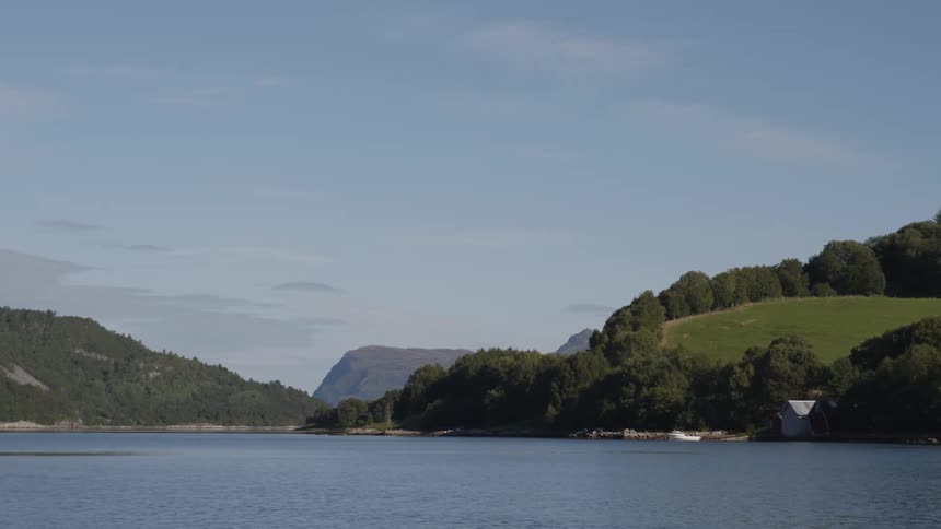 A serene lake surrounded by green hills and a clear sky
