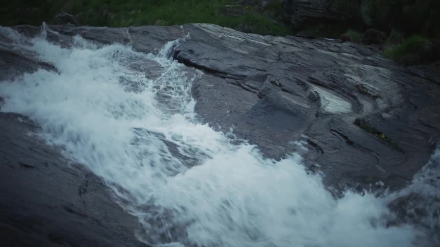 A rushing river flows down over jagged rocks