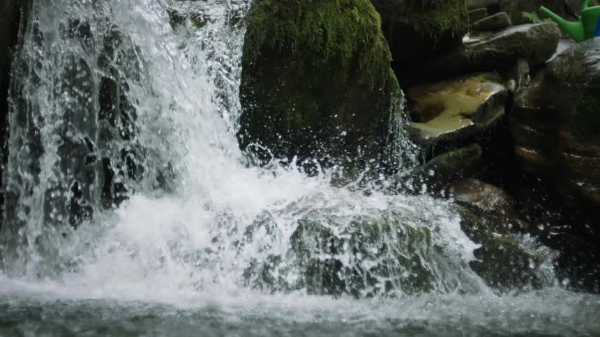 Flowing water amidst stones falling in slow motion from a river