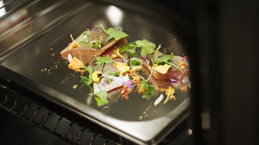 A hand inserts a metal tray with a tofu based meal in an oven