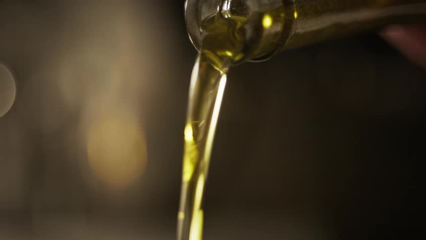 A person pours oil out of a bottle