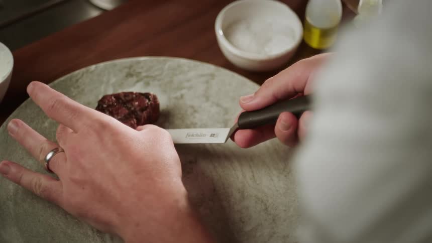 A cook serves a steak on the plate