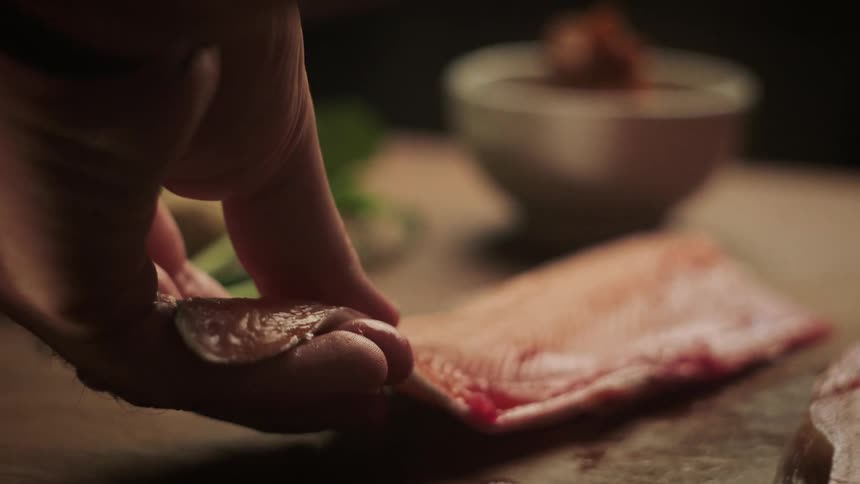A man moves a filet of fish to a table