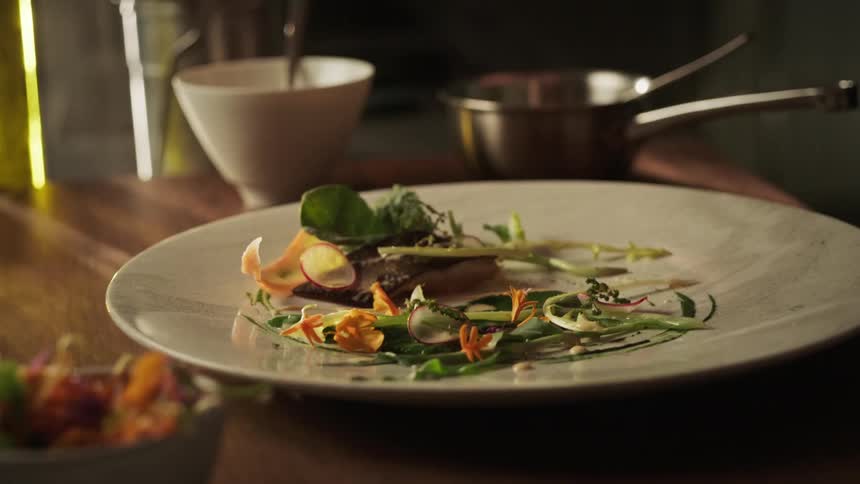 Hands of a person taking salad from a small bowl and pouring it while assembling it on a plate