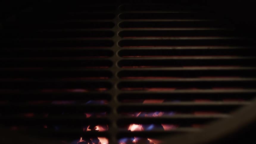 Sparks and smoke rise from fire burning under grill top
