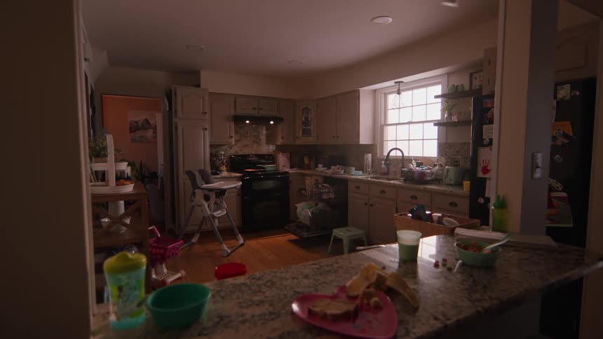 The interior of a kitchen with various childrens objects spread across the tables and floor