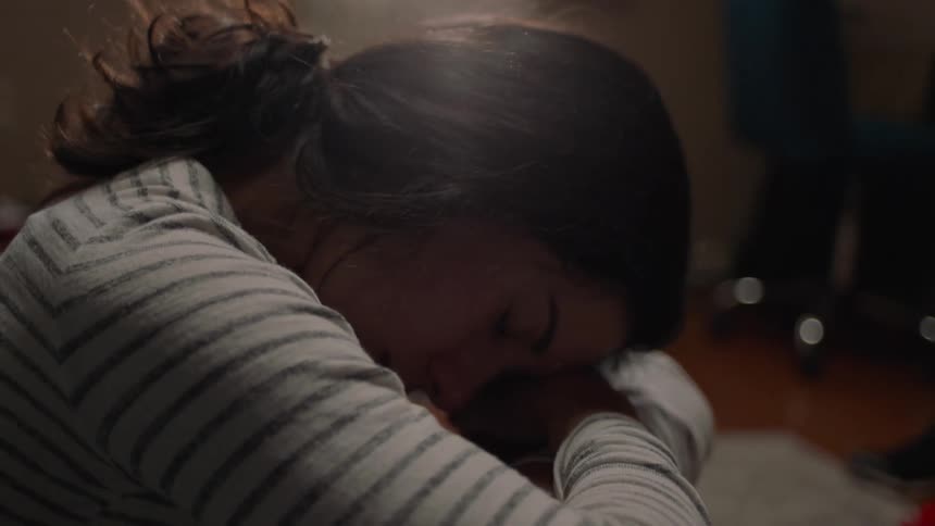 Woman placing her hands on her face and lying on her arms with a tired facial expression