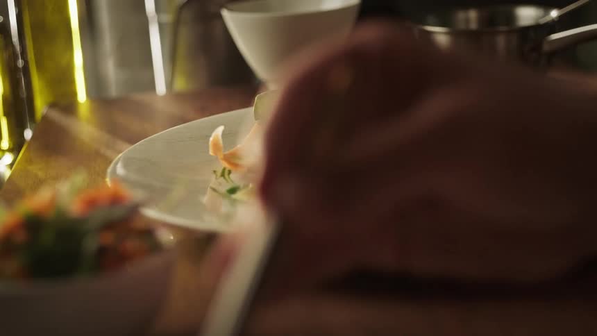 A person is plating a gourmet dish with precision