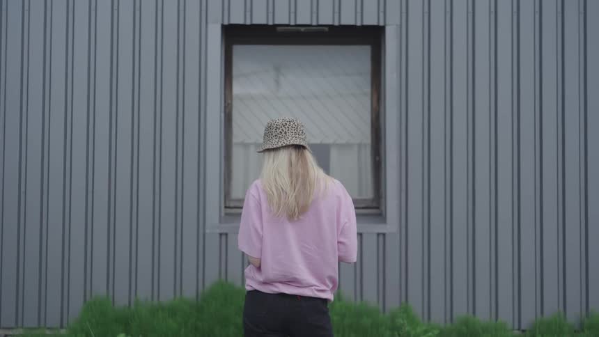 Back view of a blonde woman using her cell phone while outdoors in daylight