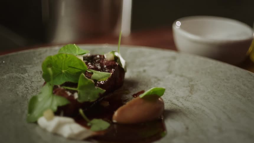 A person sprinkles coarse salt over a salad