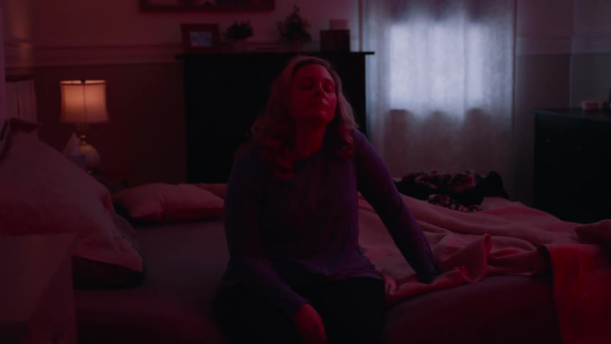 Woman sitting on the bed using her cell phone with a tired facial expression and then lying down and sleeping
