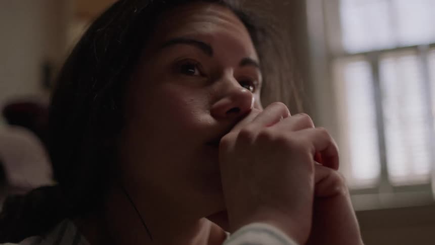 A woman is rubbing her face while sitting