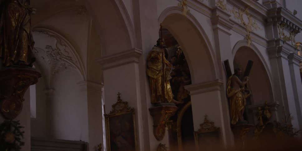 A cathedral with arches and pillars decorated with golden statues of saints