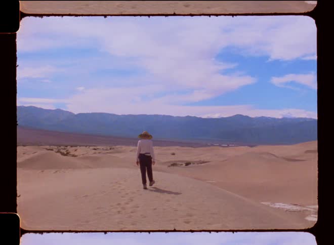 A woman walks and points in a desert