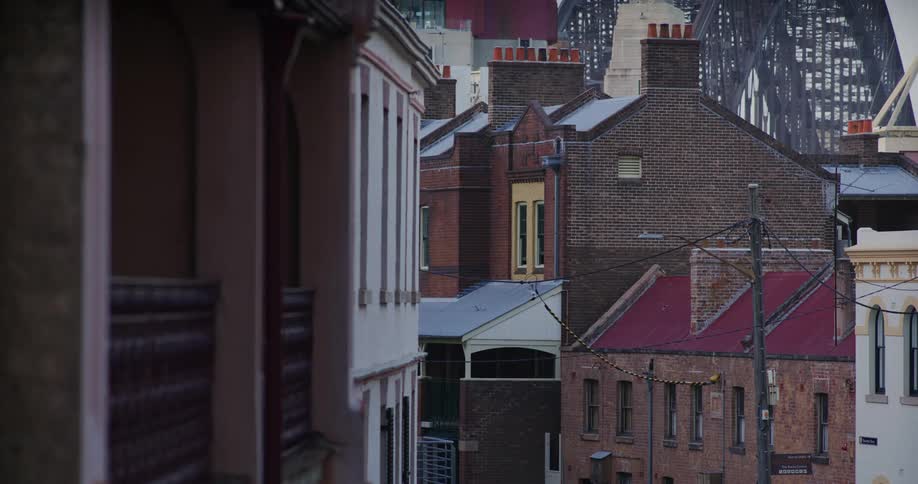 Brick buildings sit in front of a steel bridge in a dense city