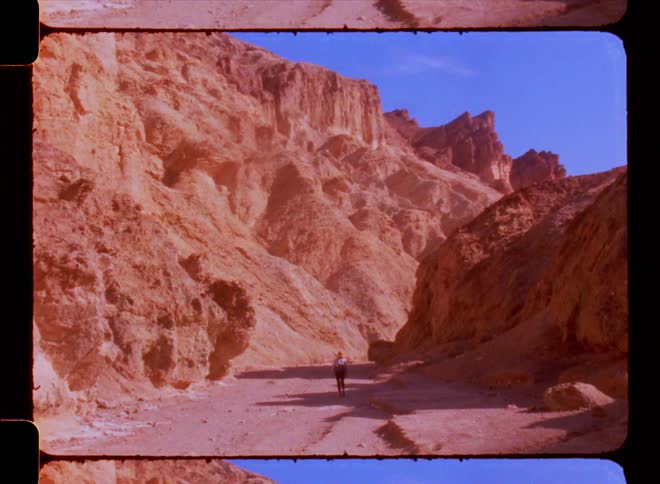 A person walking on a path between large rock formations