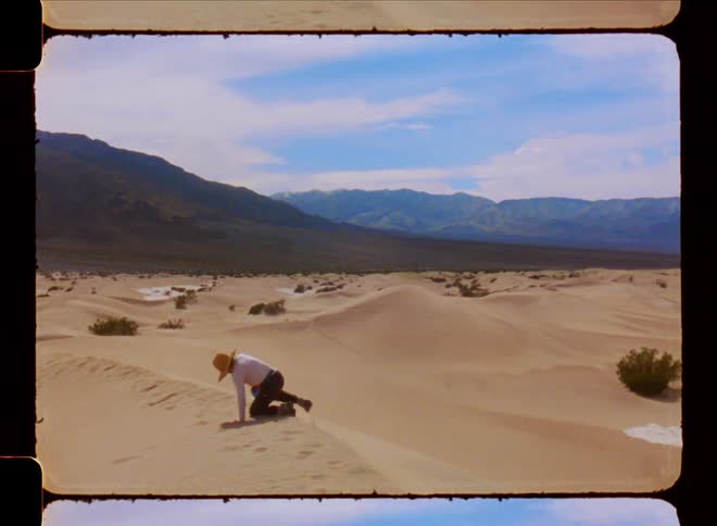 A woman stands up on a desert dune