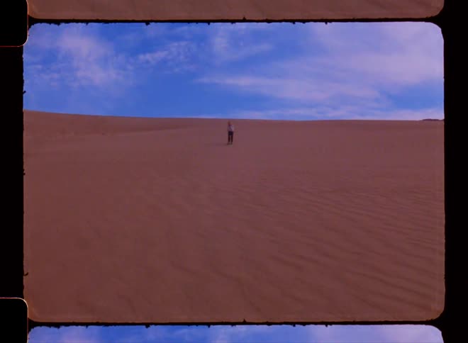 A person walks quickly down a sand dune