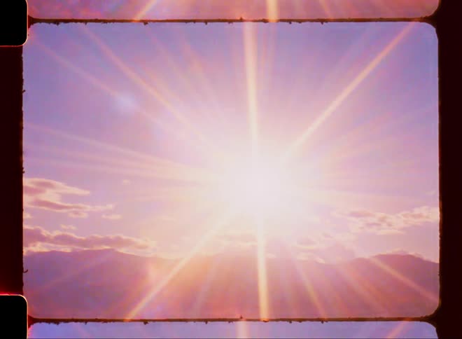Sun shines over the mountains on a clear day caught on vintage film